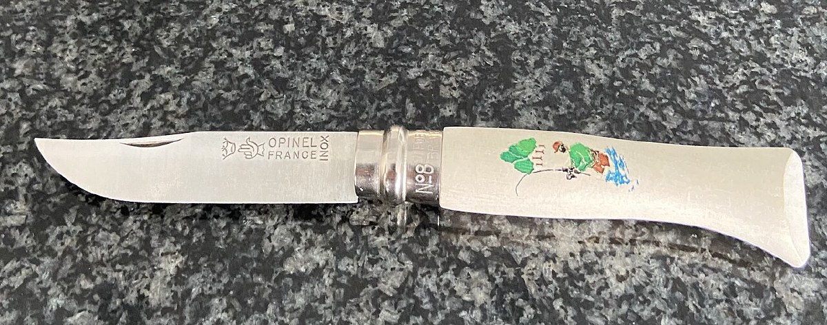 An Opinel No. 8 knife open on a granite surface — stainless Inox variant with a decorated handle; the blade stamp and No 8 collar are visible
