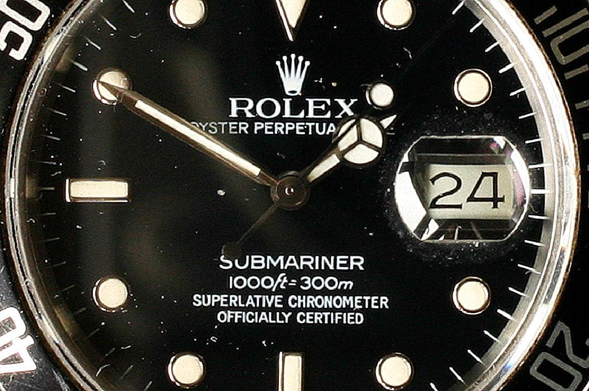 Macro photograph of a Rolex Submariner Date dial showing the Superlative Chronometer Officially Certified text, 300m depth rating, and date window